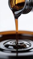 Close-up of thick dark syrup pouring from bottle into a shiny metal container photo