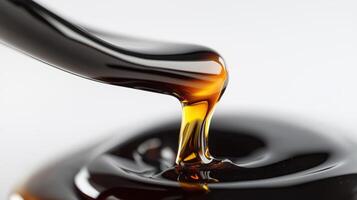 Close-up of golden amber maple syrup pouring from a spoon into a dark pool of syrup photo