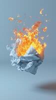 Crumpled paper on fire with bright flames against a gray background photo