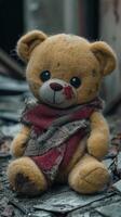 Worn and torn yellow teddy bear with red scarf in an abandoned setting photo