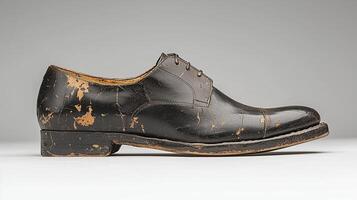 Worn black leather dress shoe with distressed finish and cracked surface photo