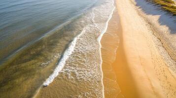 Aerial view of golden sandy beach with gentle ocean waves and clear blue water photo