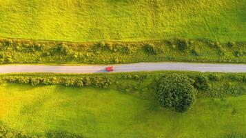 Aerial view of countryside road with red car in lush green fields photo
