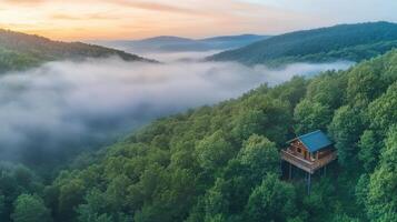 Remote mountain cabin overlooking foggy forested hills at sunrise photo