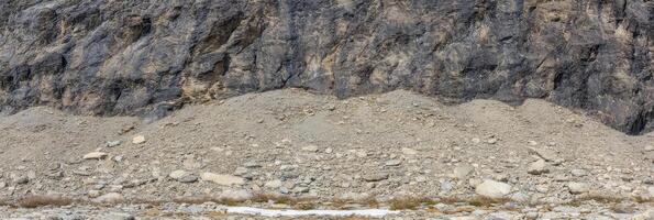 Rocky cliff face with loose debris and gravelly terrain in natural setting photo