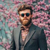 A man with a beard and sunglasses standing in front of a flowering tree photo