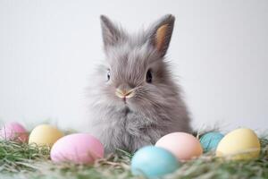 A small gray rabbit is sitting in a pile of colorful eggs photo