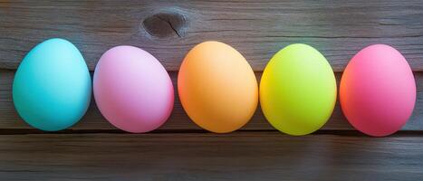 Five different colored eggs are lined up on a wooden surface photo