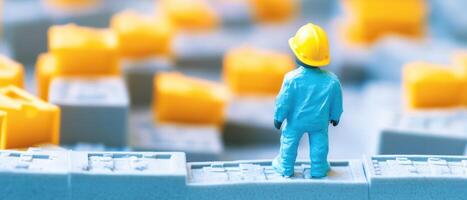 A miniature person in a hard hat standing on top of a building photo