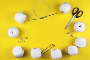 White yarn and knitting accessories lie on a yellow background. Space for text. Business concept photo