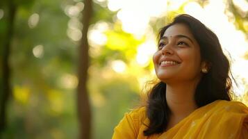 Beautiful Indian Woman Smiling and Looking Upward in Yellow Sari at Sunset photo