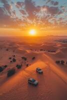 Desert landscape with sand dunes, sun setting. Two vehicles driving on sand. Golden hour light shining down, adventure, exploration, open space, travel destination. photo