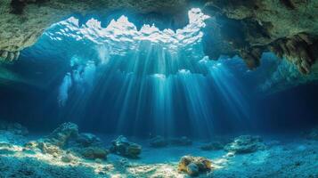 Underwater Cave Scene. Sunlight streams through clear blue water. Rocks and sand cover the sea floor. Bubbles rise towards the surface. photo