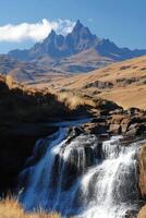 Mountain Peaks view behind Waterfall. Nature scene with water flowing down rocks. Clear sky above landscape. Peaceful outdoors scenic. photo
