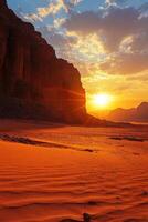 Desert landscape with mountains at sunrise. Orange sand in the foreground. Bright sun with rays in the sky. Clouds on the horizon. photo