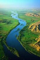 Wide river flows through a green plain. Sand banks rise on the right side. The river curves. A sunny day under a blue sky. photo