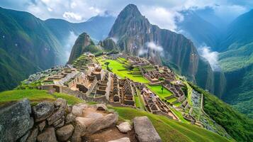 Ancient city ruins high on green mountain. Stone buildings overlook valley. Clouds cover mountain peaks. Scenic view of landscape. photo