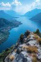 Lake view from a mountain top. Beautiful nature scenery with water and forest. Rocks in foreground. Bright sky with clouds during daytime. photo