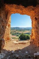 Stone Window View. Landscape with trees and clear blue sky through cave opening. Sunny day with bright light on textured rocks. Scenic landscape. photo