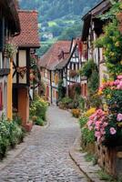 Village Street View. Cobblestone road flows between timber buildings and flowers. Countryside backdrop with green trees. Colorful summer blooms decorate the old path. photo