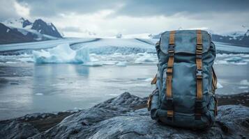 Backpack on rock. Icy water and mountains on background. Backpack ready for traveling on nature. Glacier with icebergs and clear sky. photo