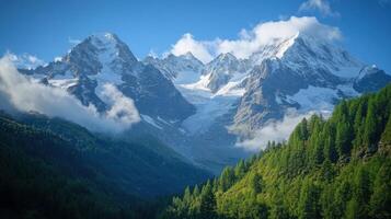 Snowy mountains rise above green trees. Clouds drift over the tall peaks. Sunny day in the high mountains. Nature scene and scenic view. photo