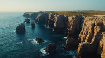 Ocean cliffs landscape. Rugged coastline with rocks meeting sea. Deep blue water crashes near high cliff faces. Aerial view of natural scene. photo