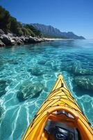 Yellow kayak sailing in clear blue water. Beautiful coastline with green trees and mountains in distance. Sunny day and relaxing scene. photo
