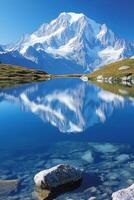 Mountain reflects in calm lake. Clear blue water with rocks at the bottom. Snow covers the mountain peak. Sunny day in nature landscape. photo