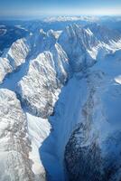 Snowy mountain peaks aerial view. Winter mountain landscape. White mountains and blue sky. Nature background. Travel and exploration. photo