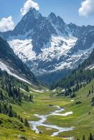 Mountain peak with snow. Green valley with a river flowing through the trees and grass. Blue sky above in summer. photo
