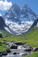 Mountain peak view. Water flows through valley. Green grass landscape with stones. Sky is bright blue. Tall majestic mountains covered in snow photo