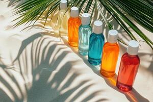 Bright liquid bottles on sand. Palm leaf shadow. Summer colors. Beach scene. Small bottles line. Color liquids in bottles. Sun and shade on sand. photo