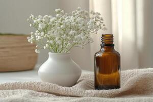 Small white flowers in a vase sit beside a brown bottle on a neutral cloth with sunlight and soft colors in a bright room photo