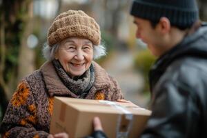 Happy elderly woman receives a delivery box from a courier outside on a cold day. She is smiling with joy. photo