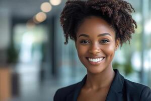 Smiling woman portrait. Dark curly hair. Black blazer. Indoor office background. Natural light. Professional look. Positive expression. White teeth. Good skin. photo
