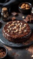 Delicious chocolate cake with glaze and nuts. Sweet dessert on a dark surface with chocolate pieces and bowls in background. photo
