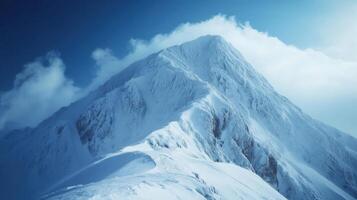 Snowy mountain peak against blue sky. Frozen ridge ascending towards a summit. White clouds surround mountain. Beautiful winter landscape on a clear day. photo
