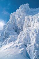 Snowy mountain peak rises against a clear blue sky. Ice crystals cover the rock face and slopes. Winter landscape. photo