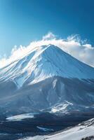 Snowy mountain peak under bright blue sky with thin white clouds. Winter landscape with mountain covered in snow. Cold outdoor scene with natural light. photo