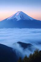 Snowy mountain peak touches soft light. Clouds fill the valley below. Forest and mountains recede into blue. Still, serene, beautiful scenery. photo