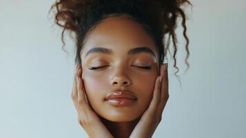 Young woman with closed eyes touching face. Serene expression with light skin. Neutral background with soft lighting. Hands on cheek. Calm peaceful mood. photo