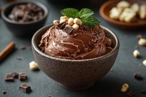 Chocolate dessert in a brown bowl. Ice cream topped with nuts and mint leaves. Sweet treat on a dark background. Food presentation. photo