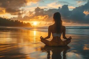 Woman in lotus pose sits on wet sand. Ocean sunset with golden light and cloudy sky. Peaceful beach scene for meditation or wellness. photo