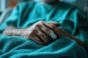 Close up of older hand resting on a blue blanket in a hospital bed with a bandage on finger. Illness concept. photo