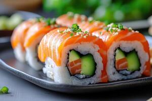 Salmon sushi rolls with rice cucumber and sesame seeds on dark plate. Japanese food close up with blurry green background. photo