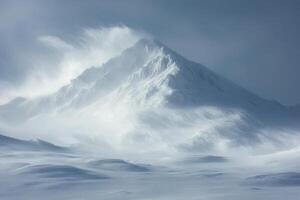 Snowy mountain peak in winter landscape. Wind and snow blowing around summit. Cold weather scene. White and blue tones. Frozen ground with drifts. photo