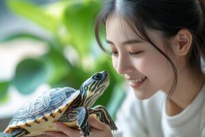 Young person smiles at small turtle held in hands. Pet care. Green plant backdrop. Reptile close up. Serene expression. Indoor scene. photo