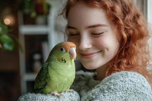 Smiling woman with red curly hair holds a green parrot gently. Bird sits comfortably. Bright indoor scene near a window with plants. photo