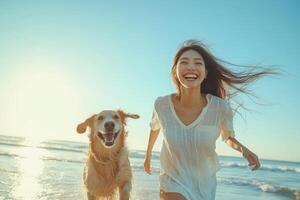 Happy woman and golden dog run together. They are on beach near ocean. Sky is blue. Sunlight is shining. Both are smiling. photo